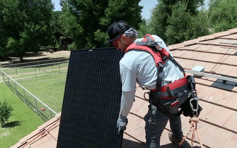 Sun valley solar worker holding solar panel on roof